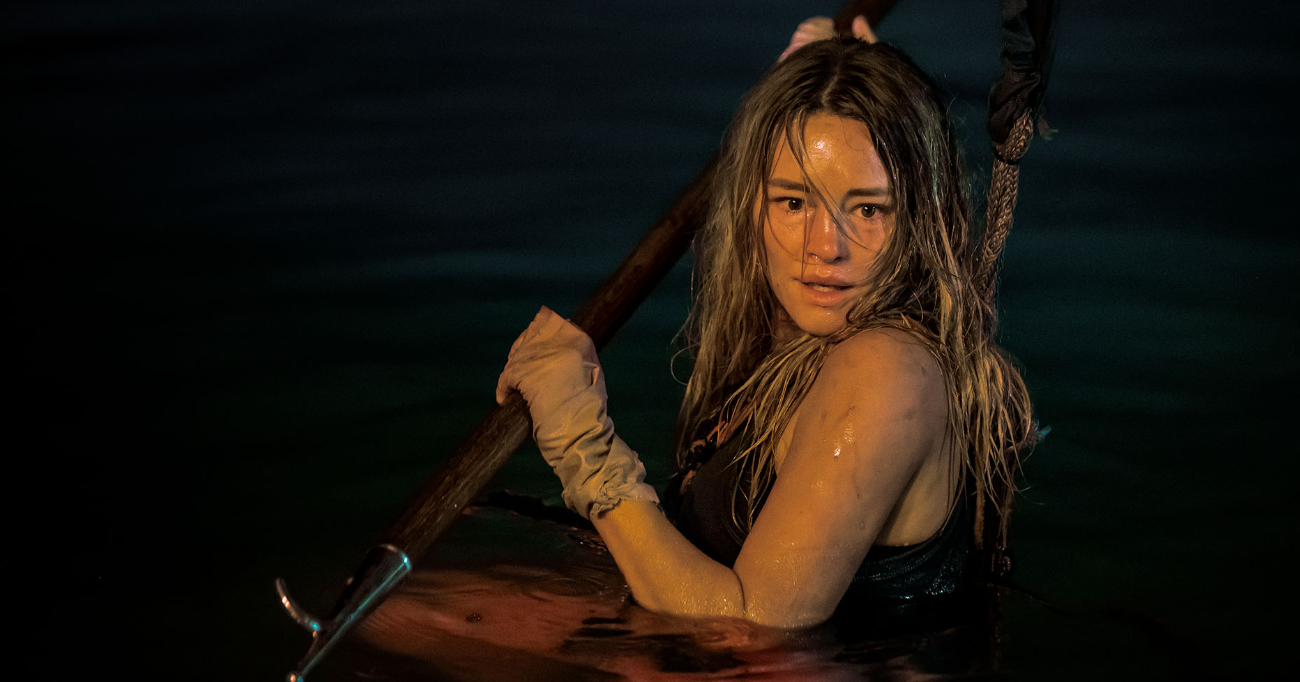 Vale a pena - Entre tubarões e um assassino obcecado, Zephyr (Hassie Harrison) mostra que a verdadeira força está em não desistir da luta pela sobrevivência.Foto: Reprodução/Internet.